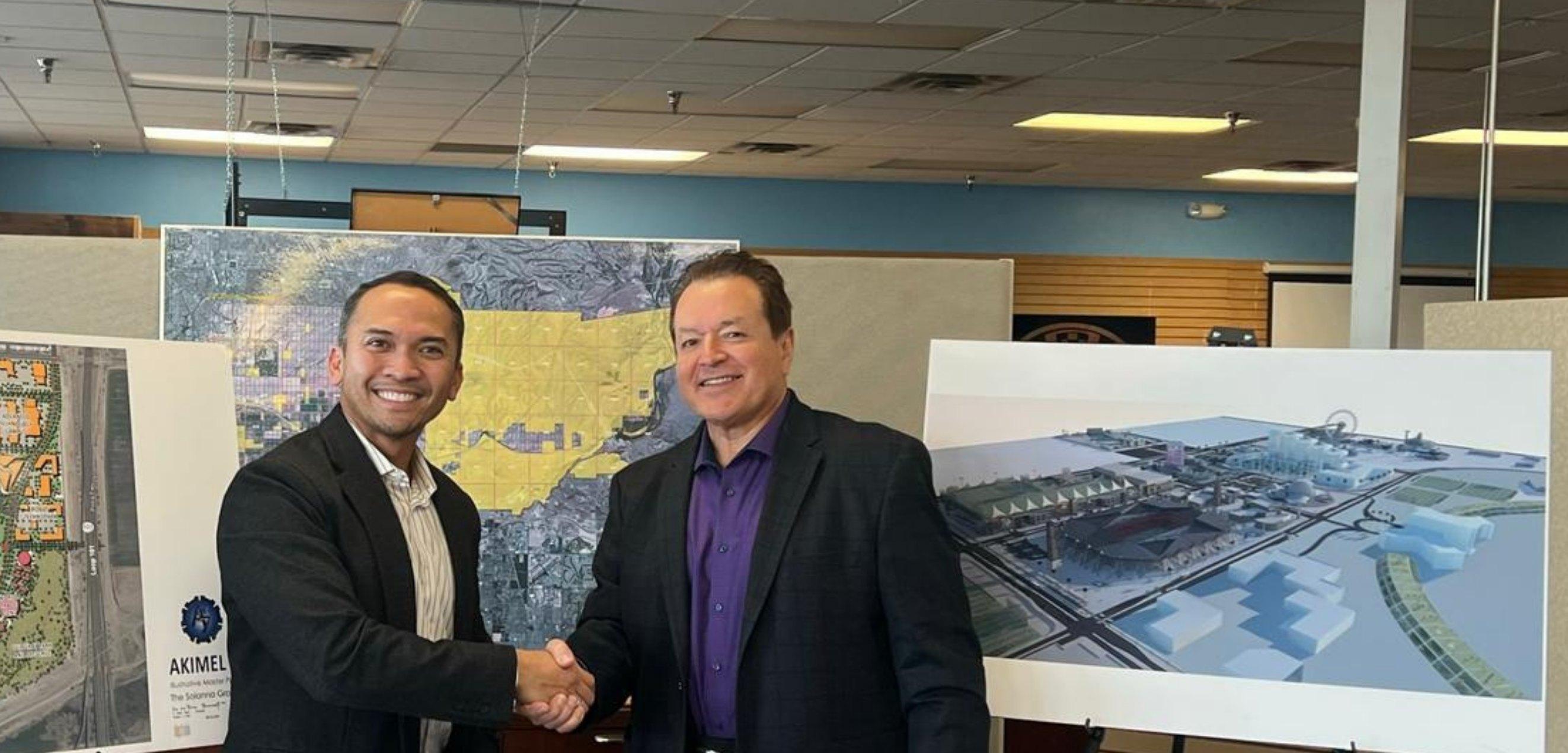 A handshake at the signing of the Akimel 7 MoU in Arizona, with site plans on easels