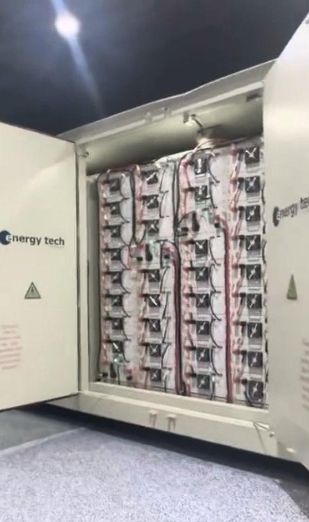 A storage container with its doors open, showing battery racks inside